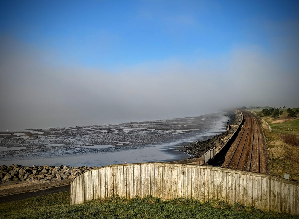 brown wooden fence on green grass field near sea