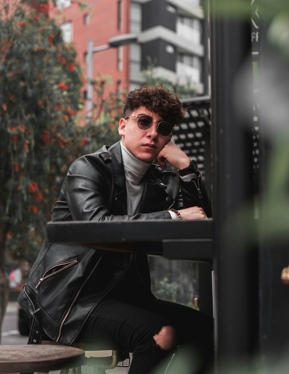 man in black suit jacket and black sunglasses sitting on black wooden bench