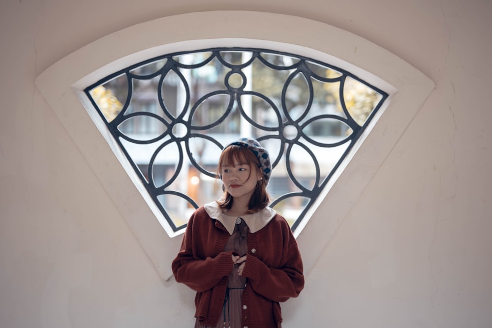 woman in brown coat standing near white wall