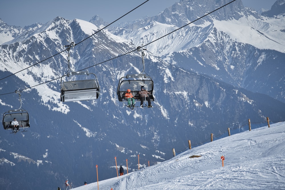 teleférico preto e cinza na montanha coberta de neve durante o dia