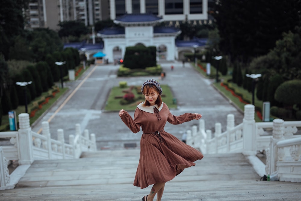 girl in orange dress standing on gray concrete floor during daytime