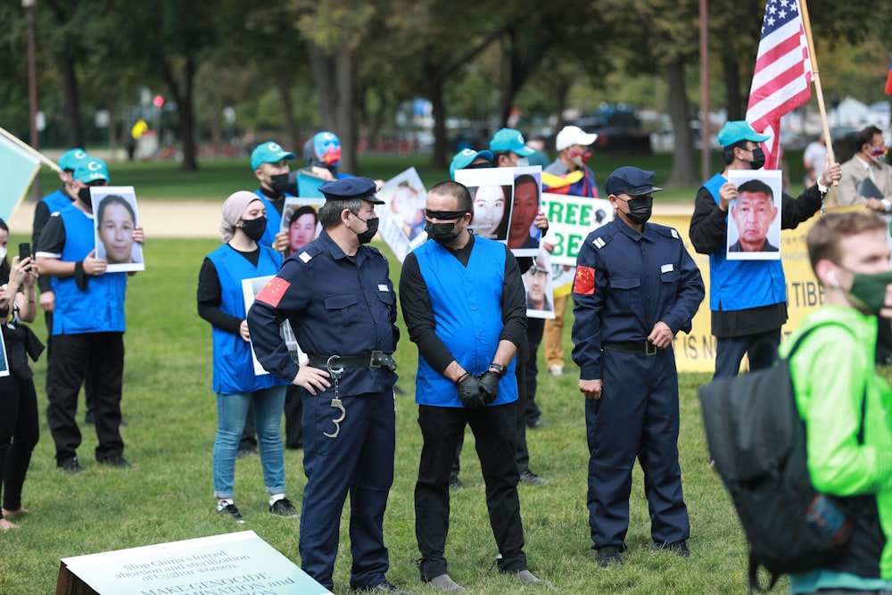 gruppo di persone che indossano l'uniforme blu e nera in piedi sul campo di erba verde durante il giorno