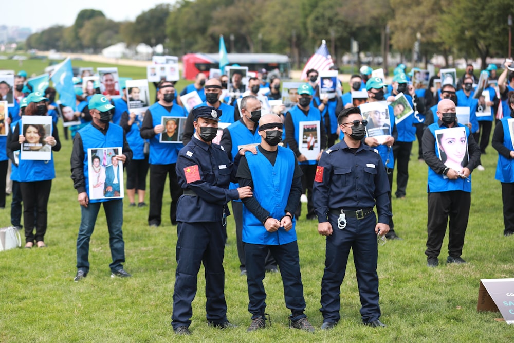 낮 동안 푸른 잔디밭에 서 있는 파란색 경찰 제복을 입은 남자