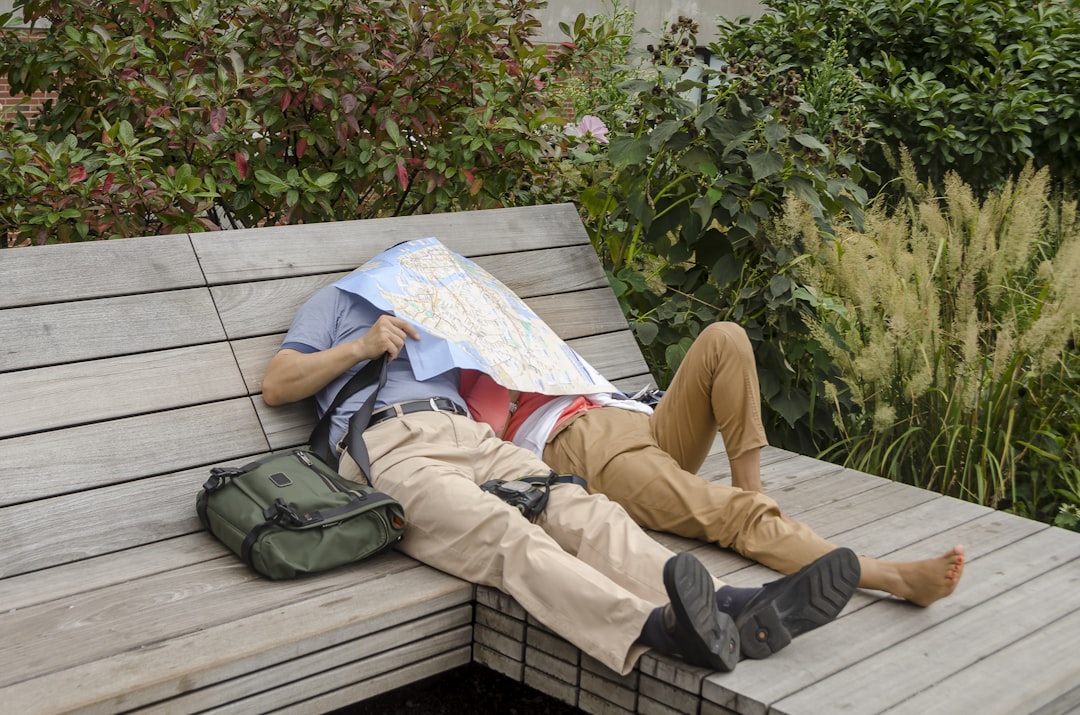 person in brown pants and gray shoes sitting on white wooden bench, take a rest on the highline trail in manhattan