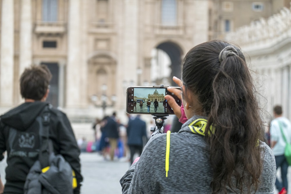 woman in gray hoodie holding black smartphone