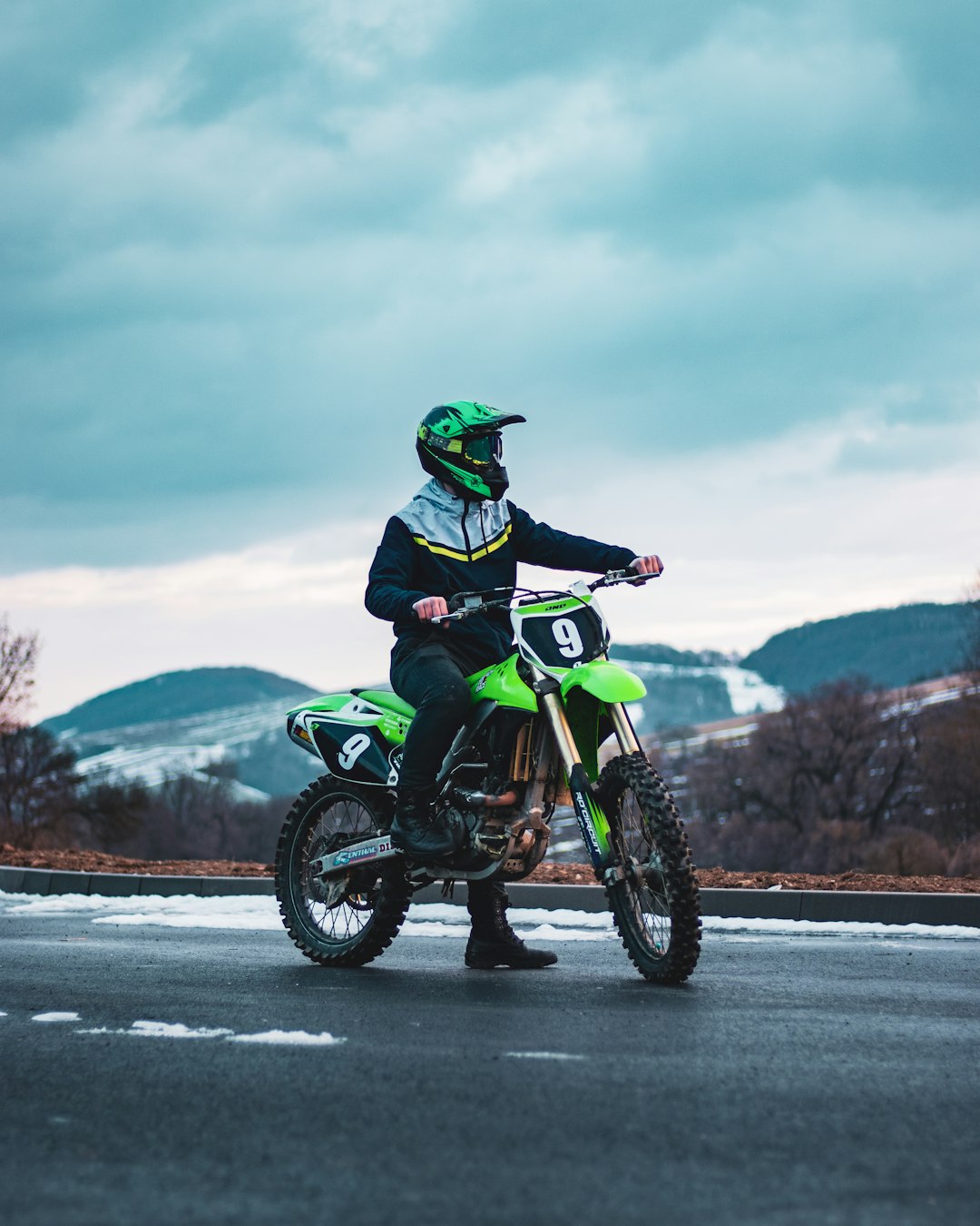 man in green jacket riding green motorcycle on road during daytime
