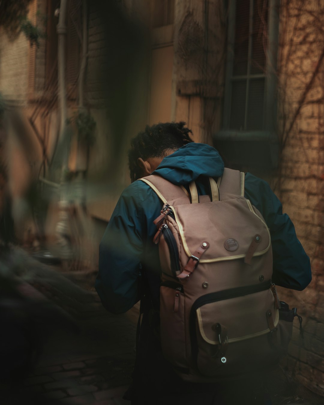 man in black jacket and blue backpack walking on sidewalk during daytime