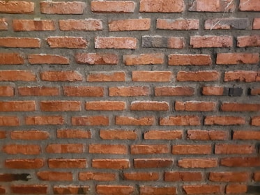 Rows of reddish-brown bricks aligned in horizontal layers and set with gray mortar.