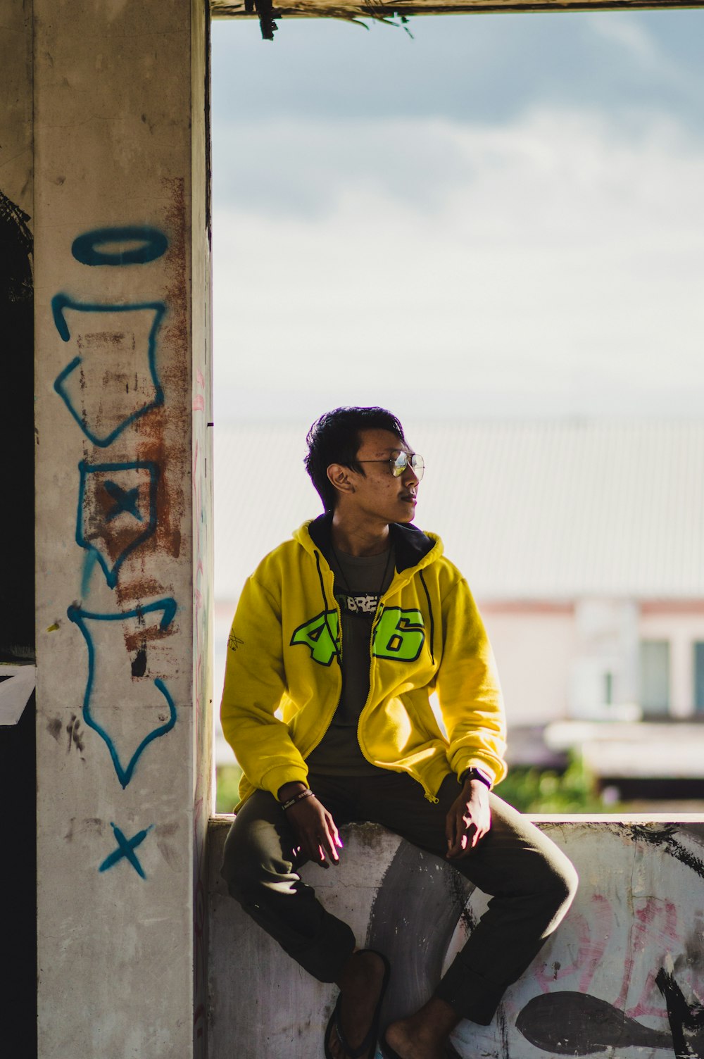 Foto Hombre con chaqueta nike amarilla y negra sentado en una pared de  hormigón durante el día – Imagen Malang gratis en Unsplash