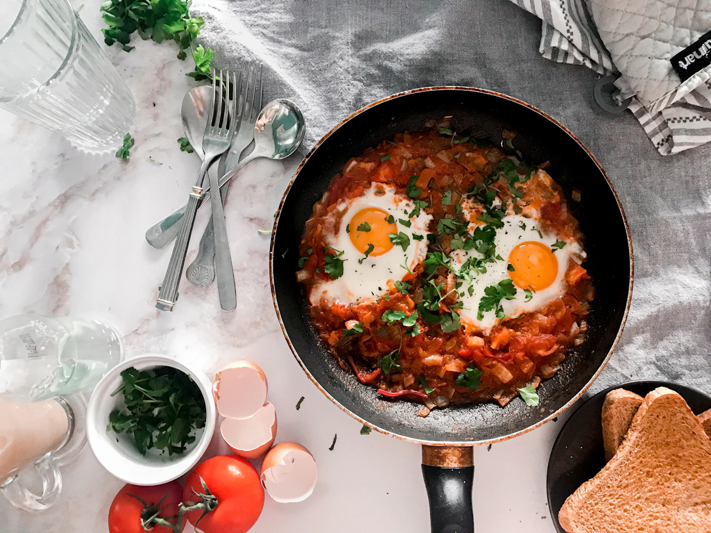 Shakshuka with eggs simmered in tomato pepper sauce in a black skillet
