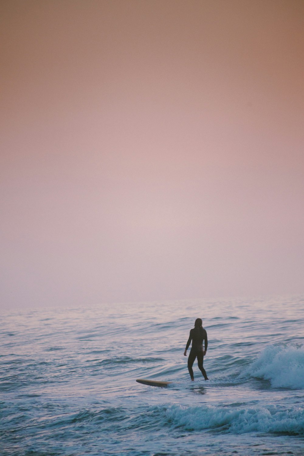 man in black wet suit standing on sea shore during daytime