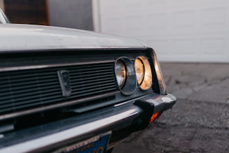 Close-up of a beautifully restored vintage car parked beside a rustic garage.