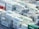 A densely packed arrangement of shipping containers, predominantly white with the word 'EVERGREEN' in green, stacked in an orderly fashion at a shipping port. The containers are on racks and appear to be refrigerated, with visible cooling units. A few containers in red, blue, and green contrast with the majority.