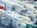 A densely packed arrangement of shipping containers, predominantly white with the word 'EVERGREEN' in green, stacked in an orderly fashion at a shipping port. The containers are on racks and appear to be refrigerated, with visible cooling units. A few containers in red, blue, and green contrast with the majority.