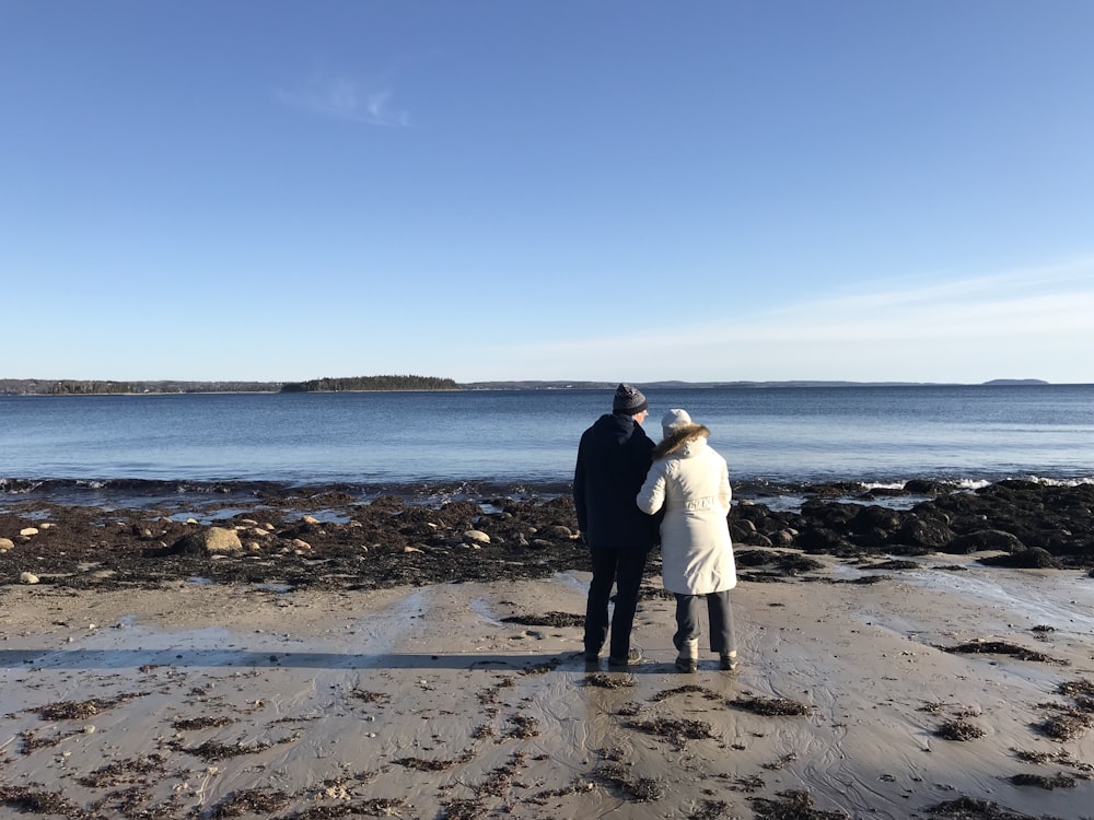 man and woman standing on beach during daytime