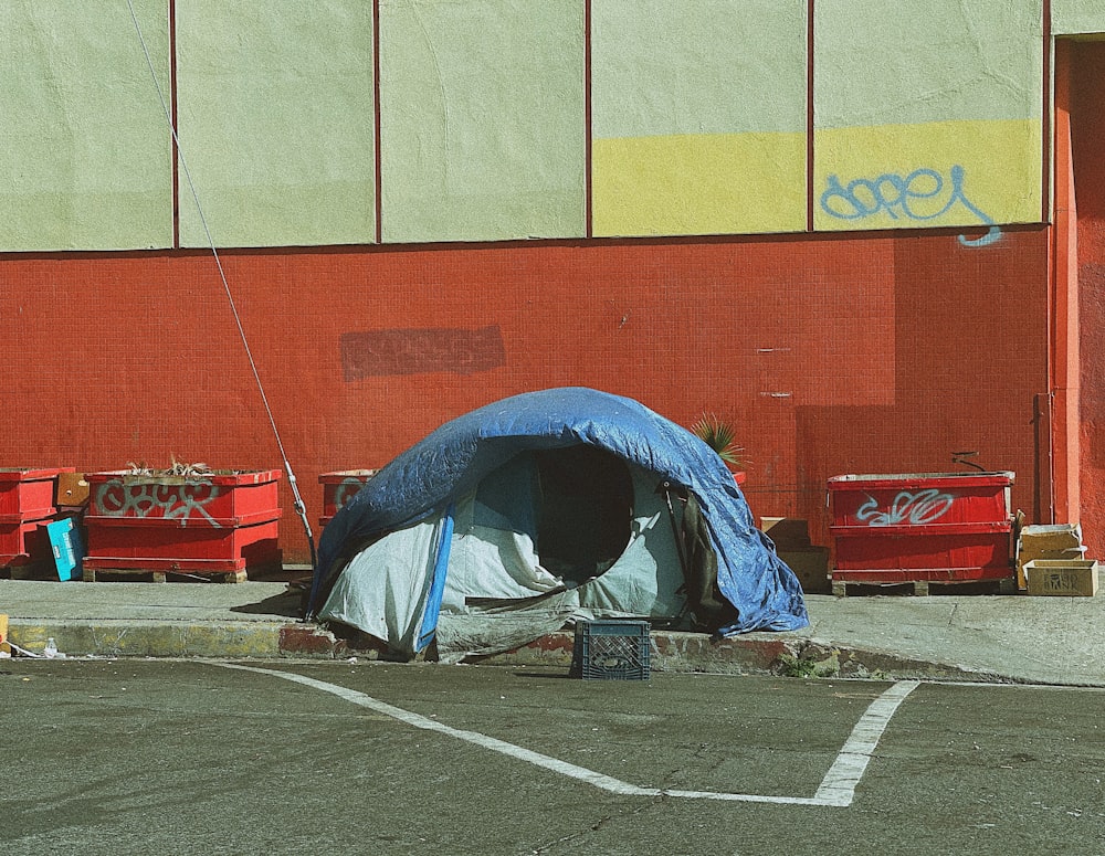 man in blue jacket lying on blue and white tent