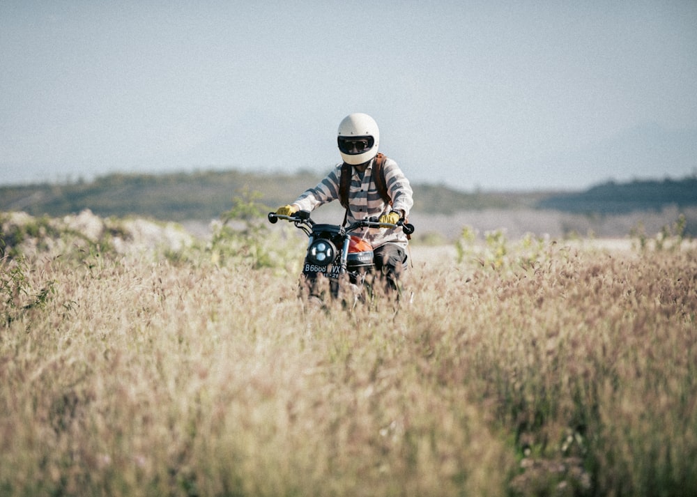 man riding motorcycle on brown grass field during daytime