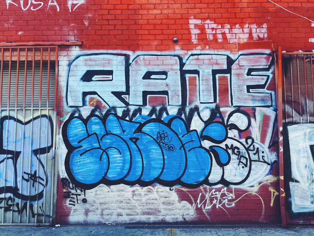 red and blue graffiti on brown brick wall