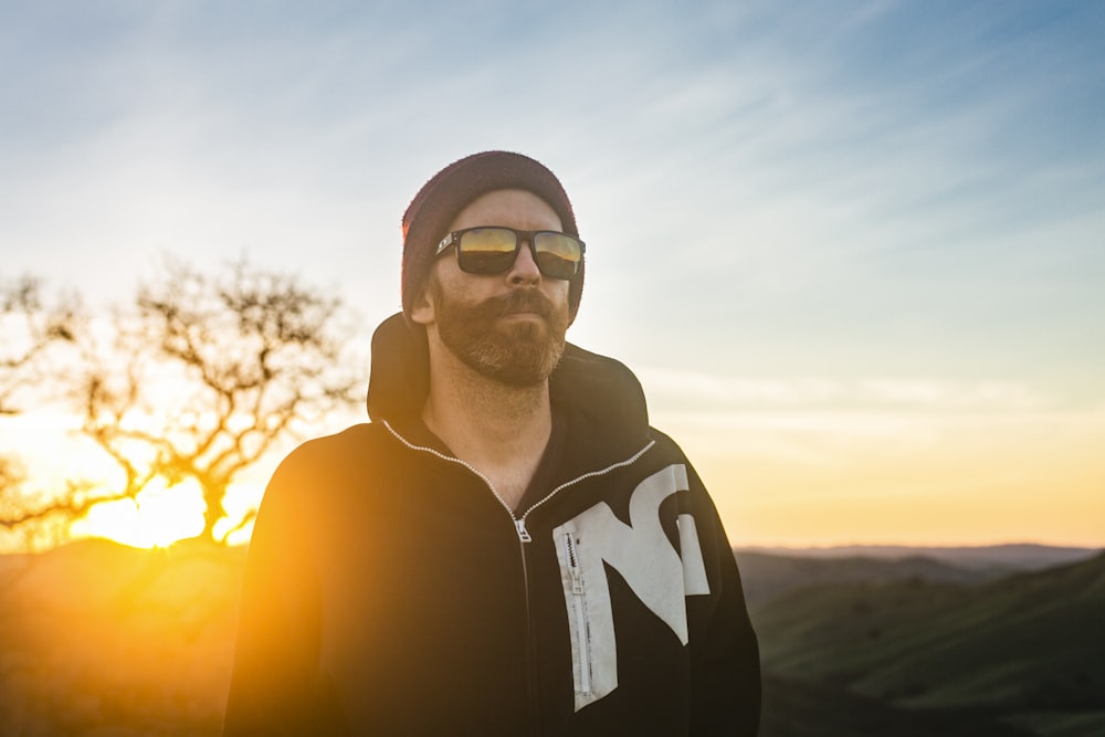 man in black and white zip up hoodie wearing black framed eyeglasses