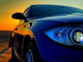 Close-up of a luxury car’s gleaming paintwork reflecting Miami’s skyline at sunset.