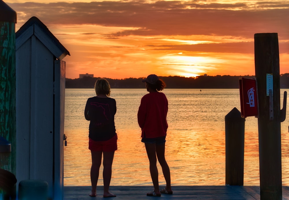 man and woman standing on beach during sunset