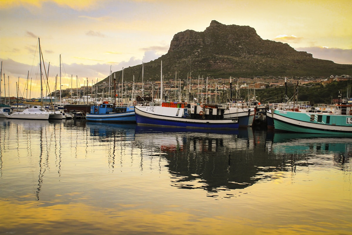 Hout Bay Cape Town — fishing boat at the harbour with mountains surrounding the bay at sunset