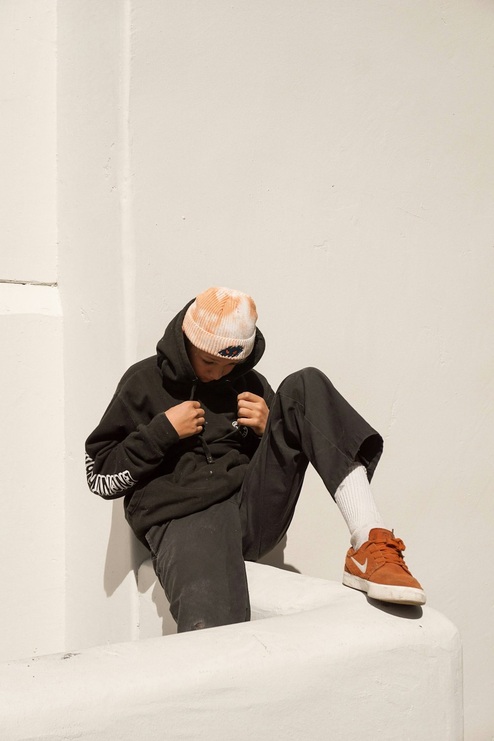 man in black long sleeve shirt and gray pants sitting on white concrete bench