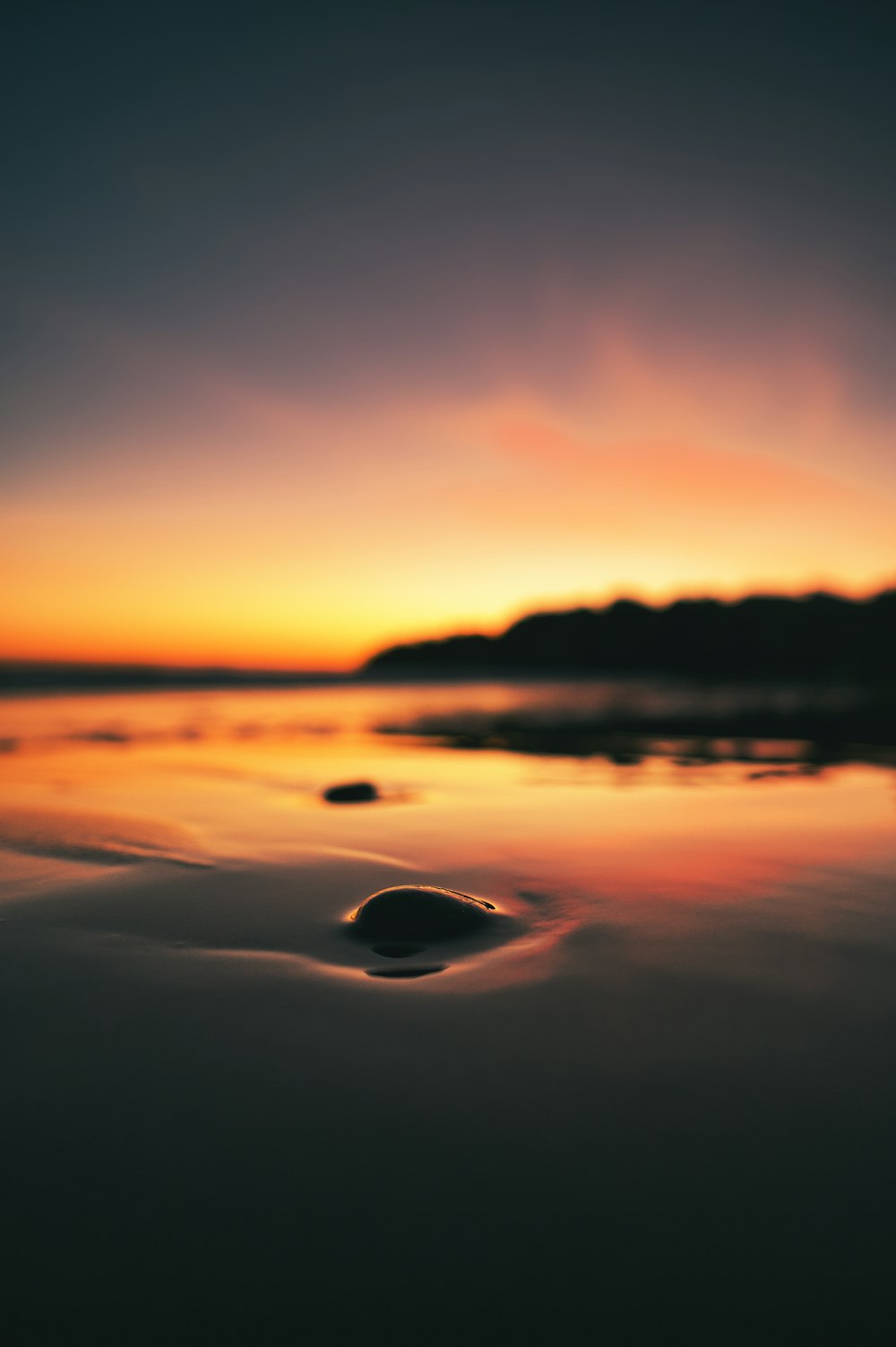 silhouette of mountain near body of water during sunset