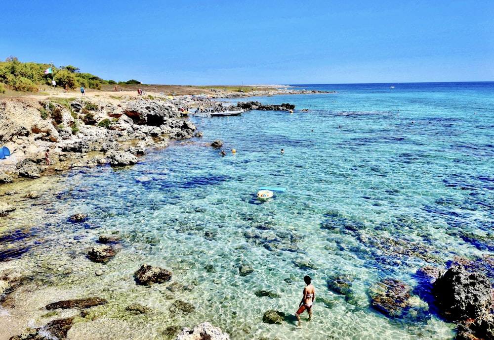 Mujer en bikini rojo de pie en la orilla del mar durante el día