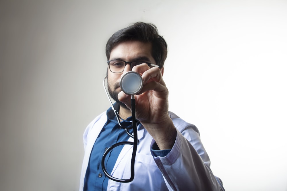 person in white shirt holding black and silver headphones