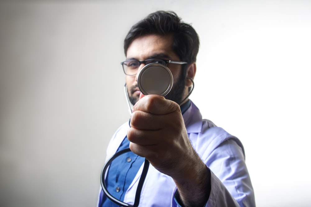 Persona con camisa blanca de manga larga sosteniendo lupa