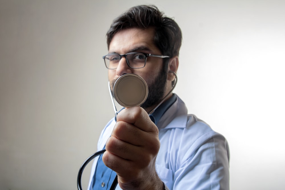 man in blue dress shirt holding black and silver headphones