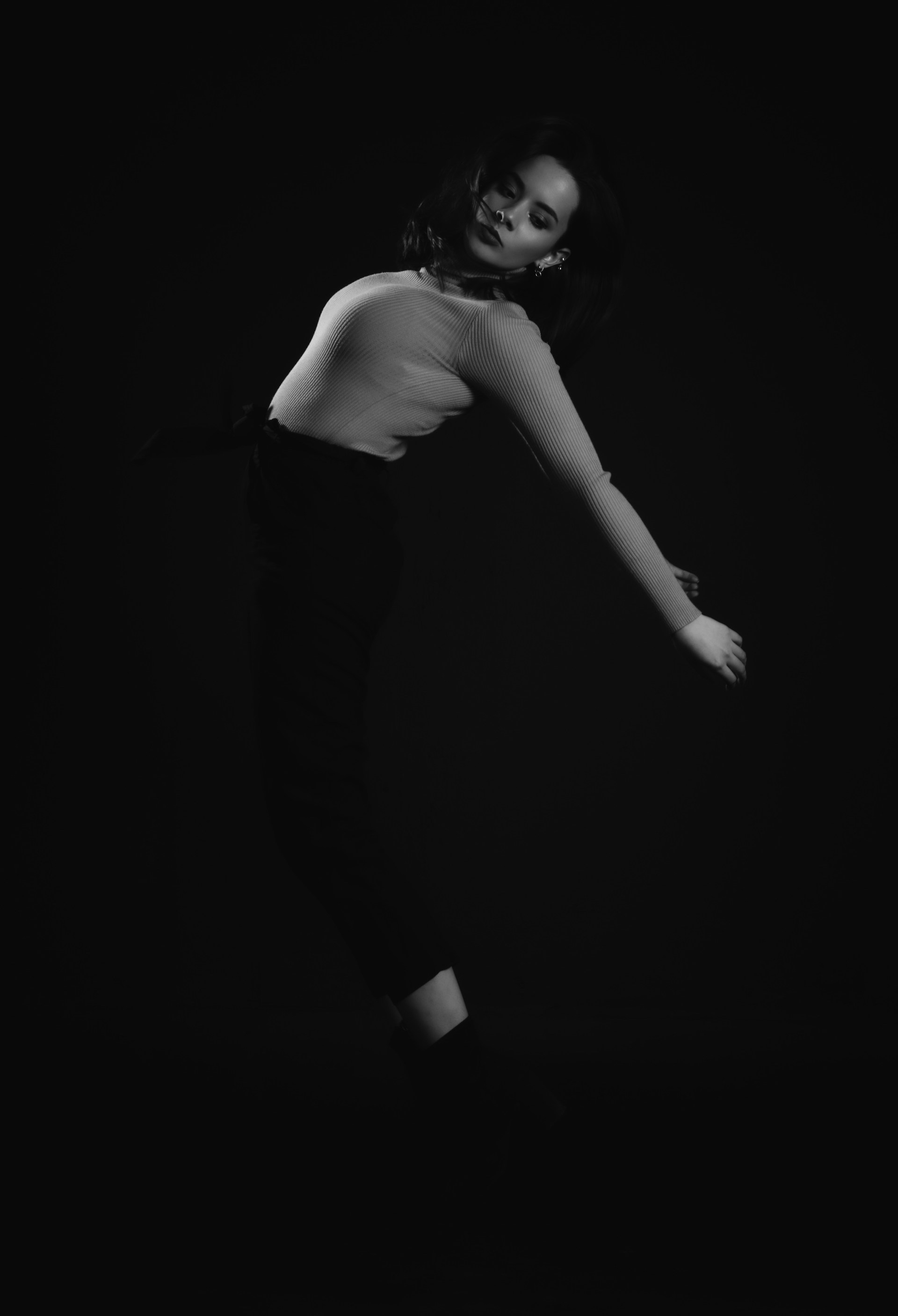 A striking silhouette of a model posing gracefully under warm golden lighting, with dark red and black gradients in the background.