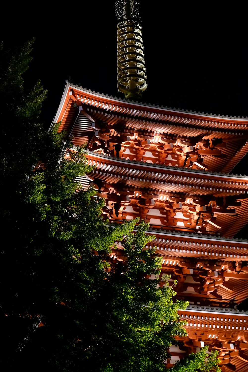 夜の緑の木々に囲まれた茶色の木造寺院