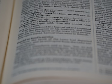 A close-up view of an open book with printed text in English. The focus is on the center of the page, with the text becoming blurred towards the edges. The text is neatly aligned in paragraphs.