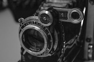 A detailed shot of the lens and mechanism of an early 20th-century stereoscopic camera.