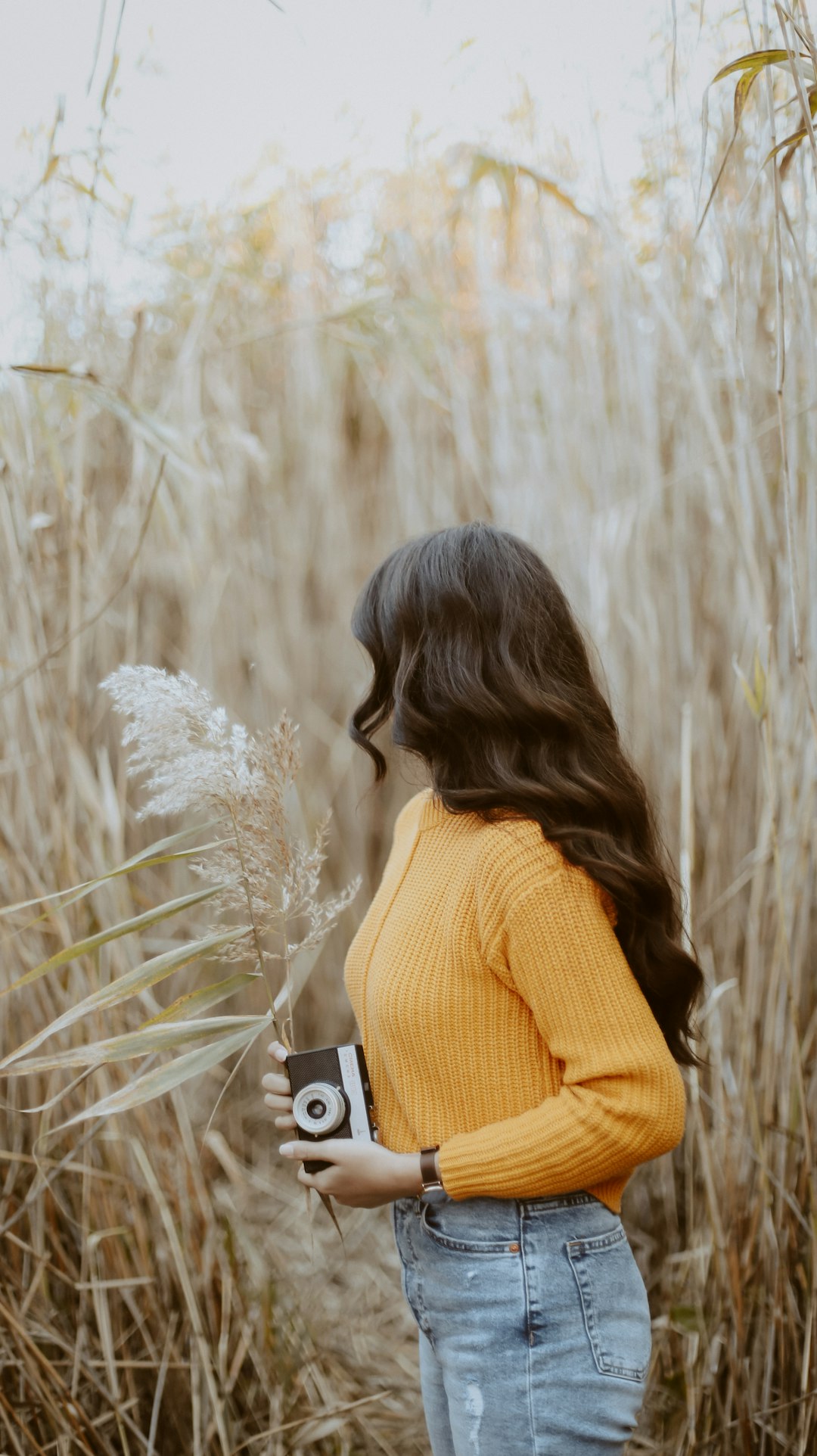 woman in brown sweater holding iphone