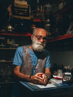 Un homme en bleu et blanc, avec une barbe blanche et des lunettes 
