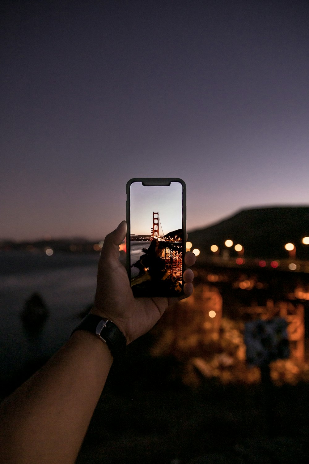 Persona sosteniendo iPhone tomando foto de la ciudad durante la noche