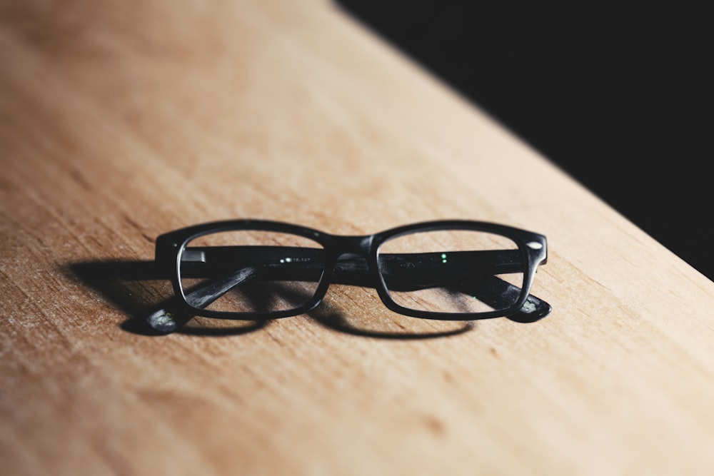 black framed eyeglasses on brown wooden table