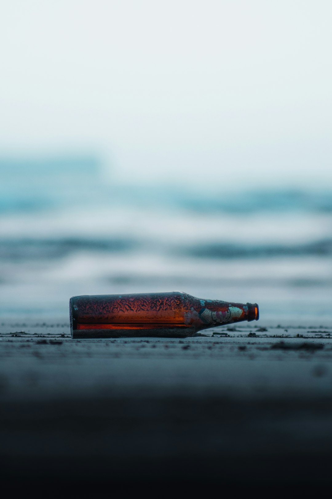 brown glass bottle on beach during daytime