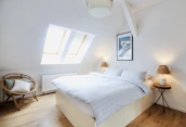 A newly finished attic bedroom with modern fixtures and natural light streaming through a skylight.
