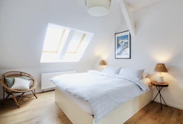 A newly finished attic bedroom with modern fixtures and natural light streaming through a skylight.