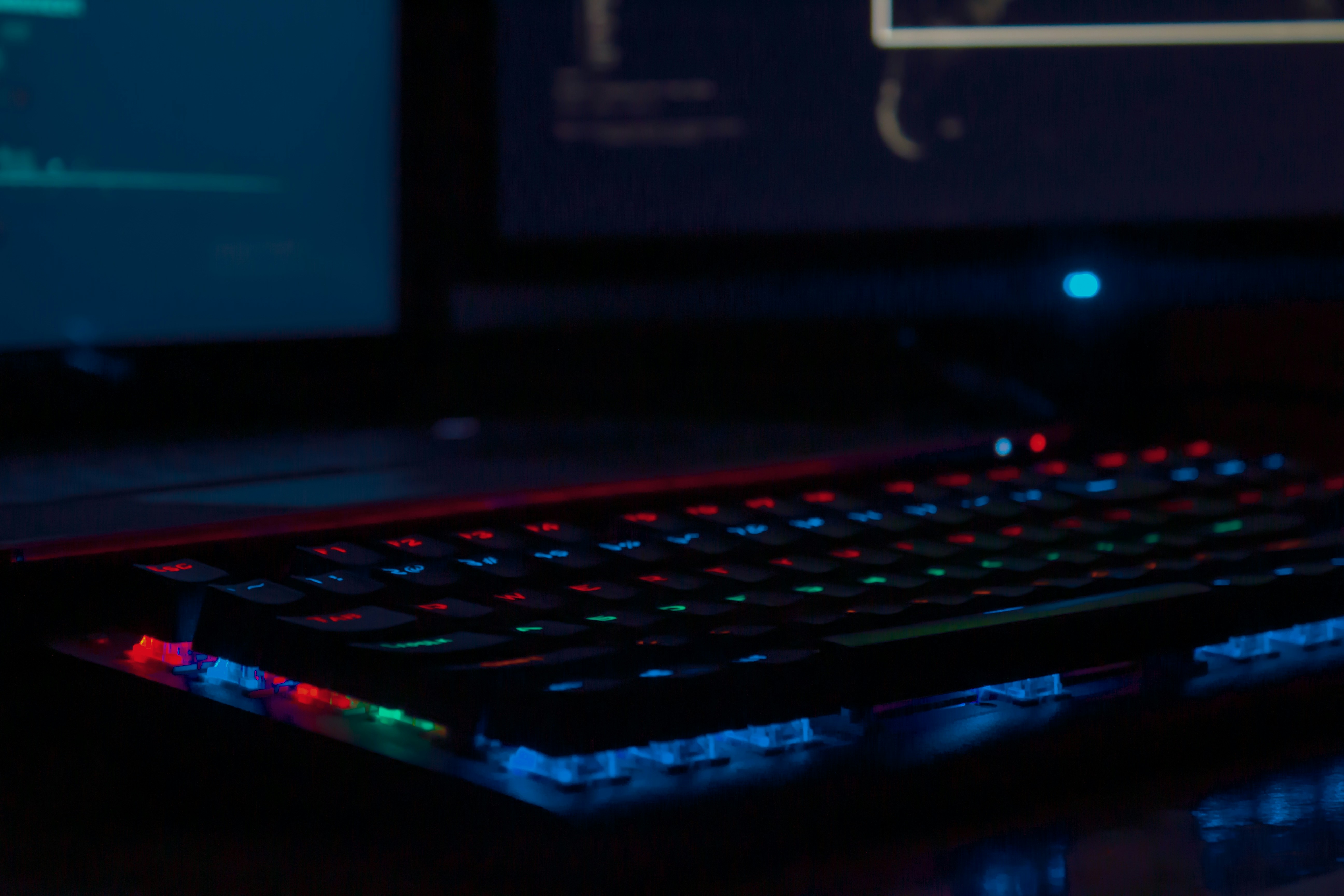 Gaming keyboard with colorful RGB lighting in dark room, moody atmospheric gaming setup