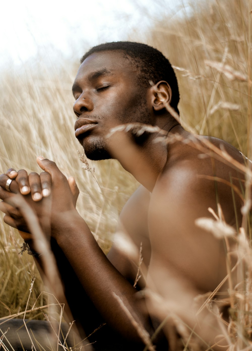 topless man sitting on brown grass field during daytime