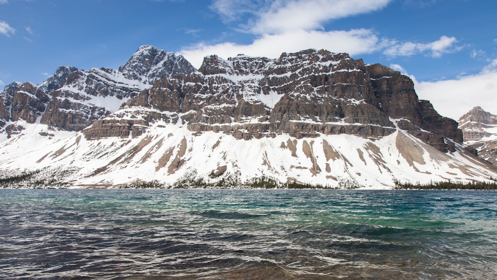 white and brown rocky mountain beside body of water during daytime