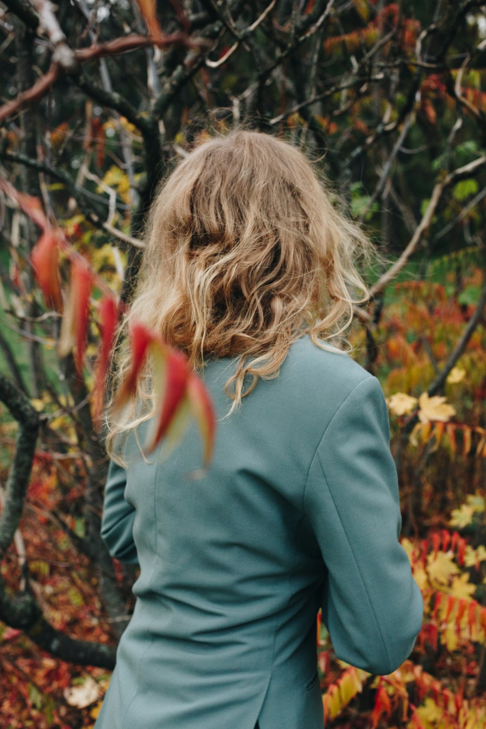 낮 동안 갈색과 녹색 식물 근처에 서 있는 회색 긴팔 셔츠를 입은 여자