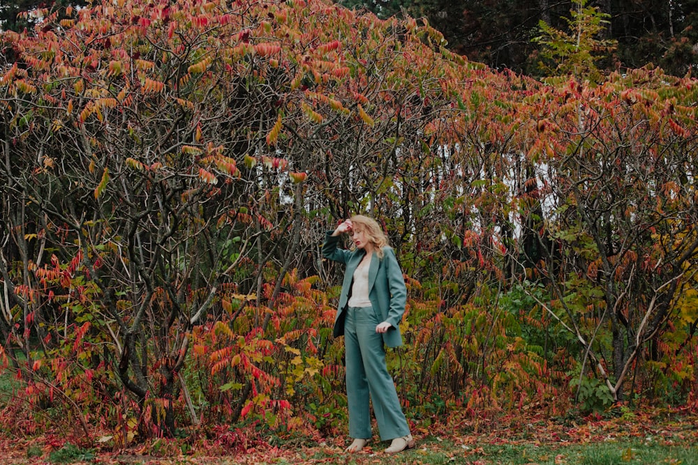 mulher na jaqueta jeans azul em pé sobre folhas secas marrons durante o dia
