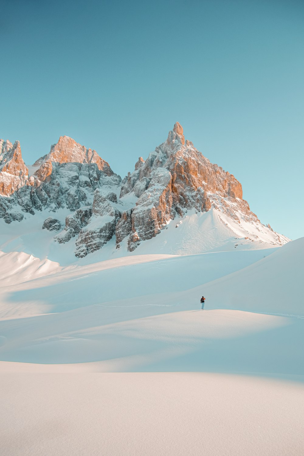 Persona che cammina sulla montagna coperta di neve durante il giorno