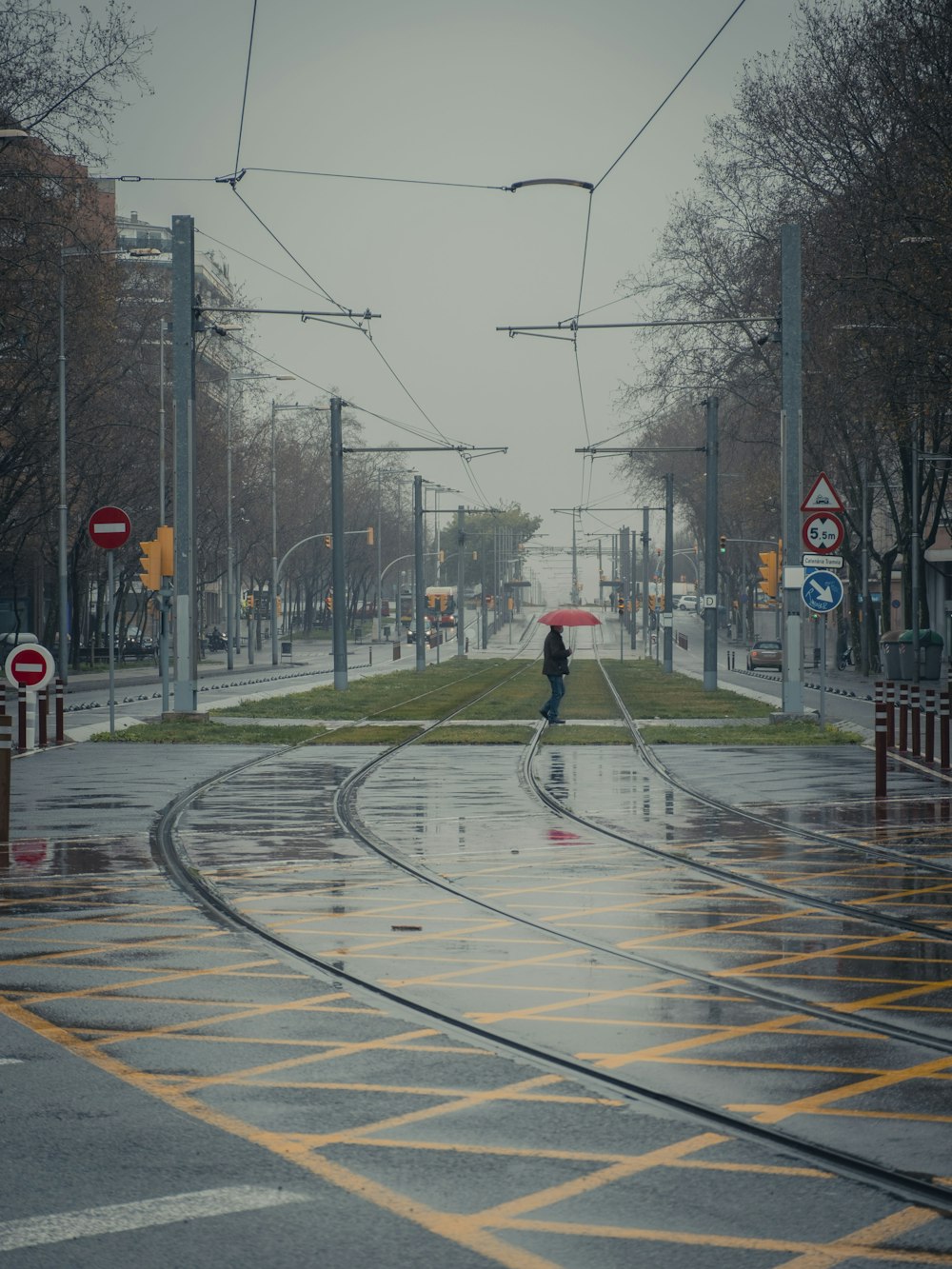 person in red jacket and black pants walking on street during daytime